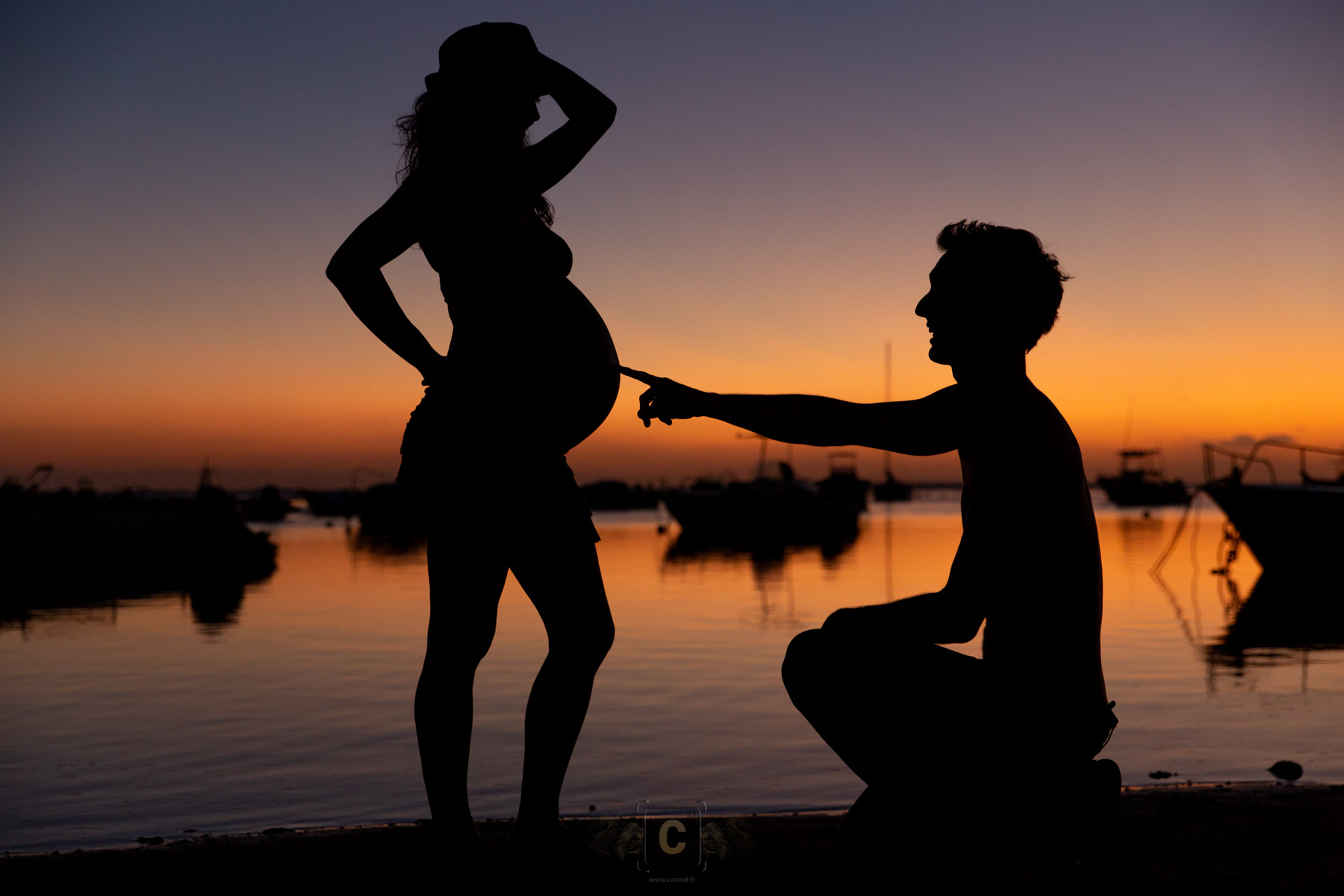 Papa montrant du doigt son futur bébé au coucher de soleil